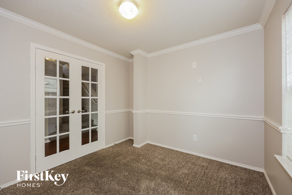 A room with a carpeted floor and a window with blinds.