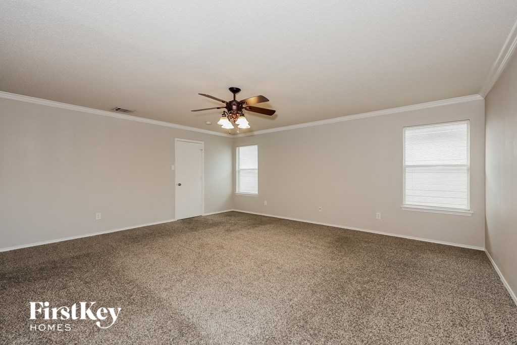 A spacious room with a ceiling fan and carpeted floor.