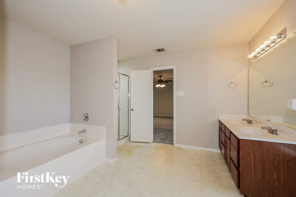 A bathroom with a white tub and a wooden vanity.