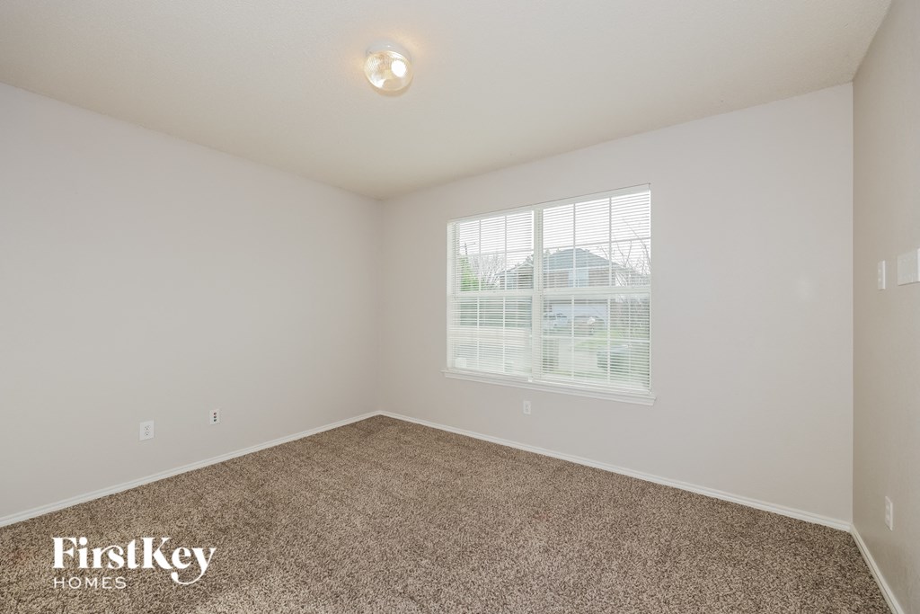 A room with a carpet floor and a window with blinds.