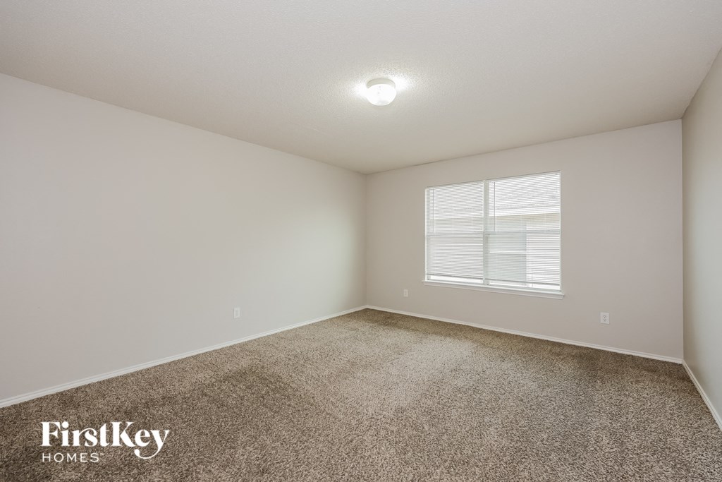 A room with a carpeted floor and a window with blinds.