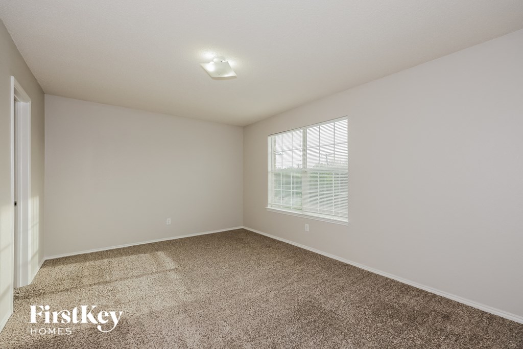 A room with a carpeted floor and a window with blinds.