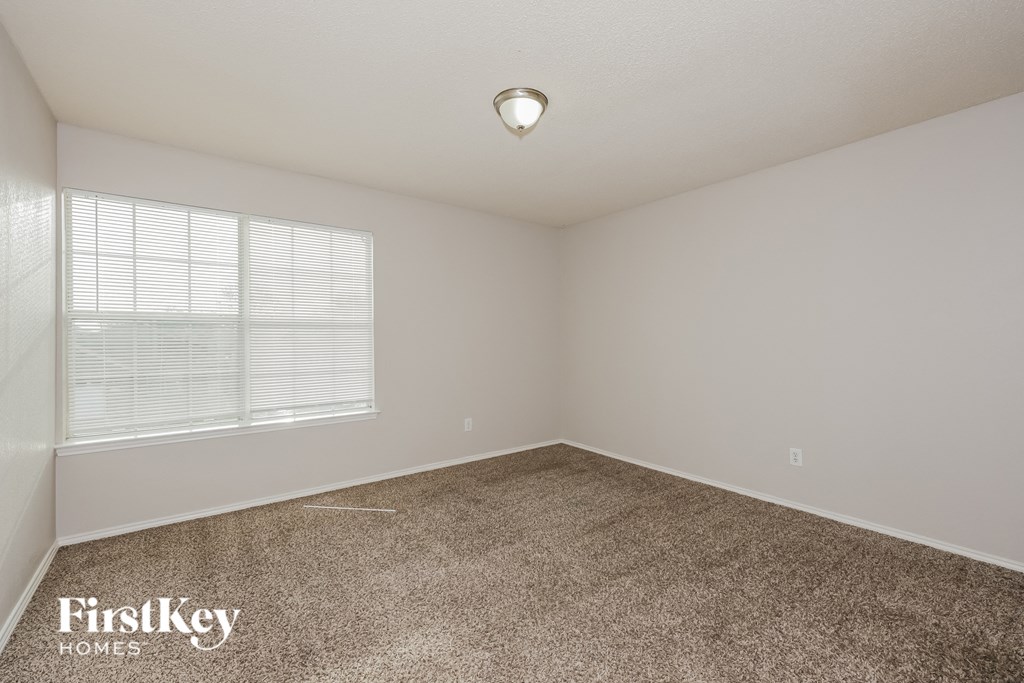 A room with a carpeted floor and a window with blinds.