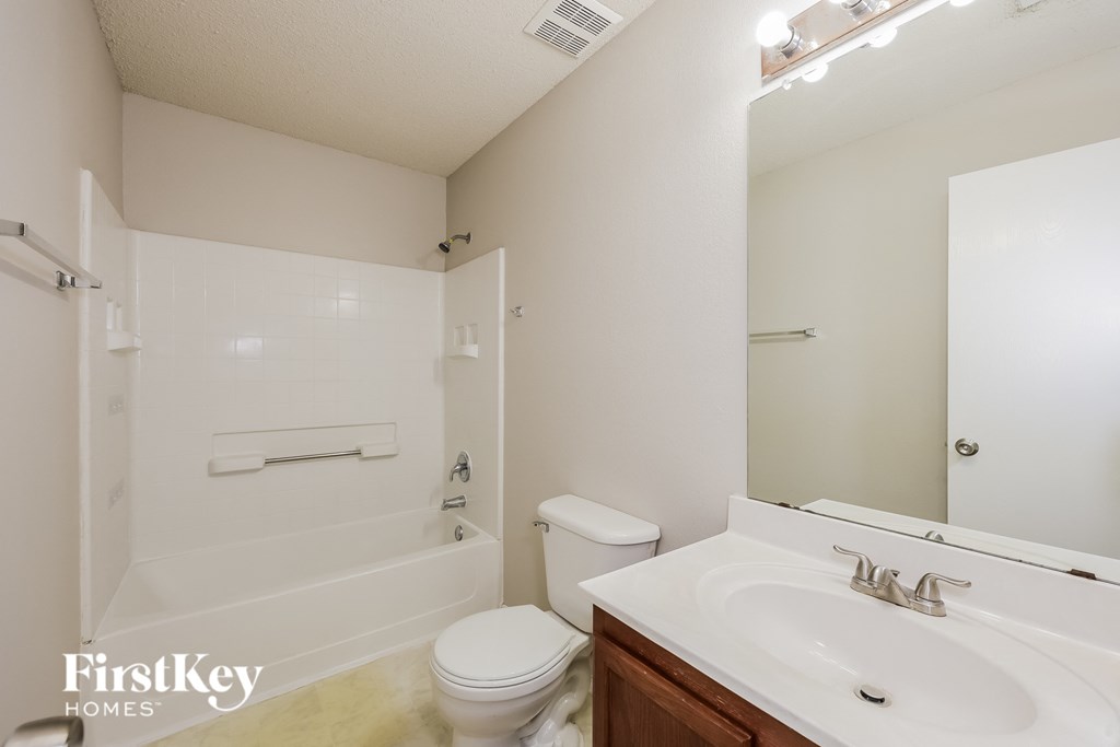 A white bathroom with a toilet, sink, and shower.