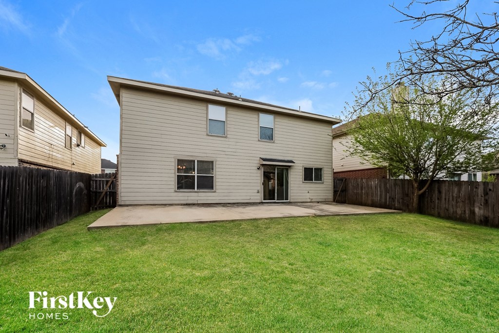 A house with a fence and a tree in the backyard.
