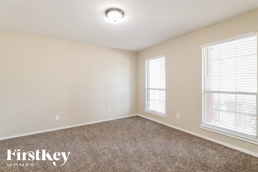 A room with a carpeted floor and a window with blinds.