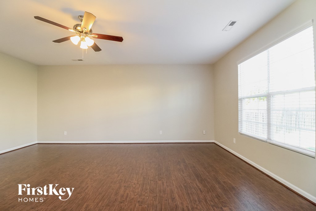 A room with a ceiling fan and wooden flooring.