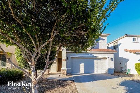 a street view of a house with a driveway and a tree