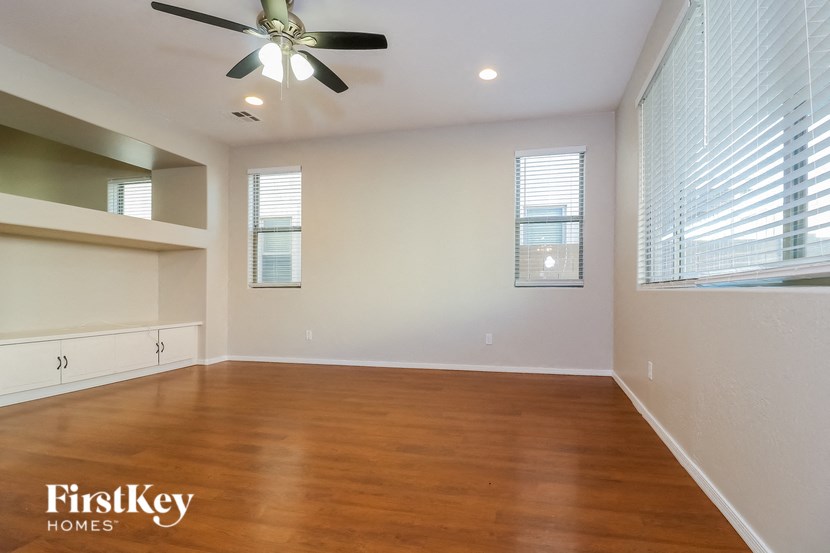 an empty living room with wood floors and a ceiling fan