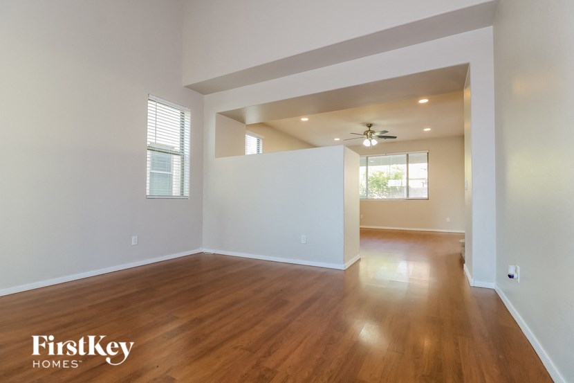 the living room and dining room with hardwood floors and a ceiling fan