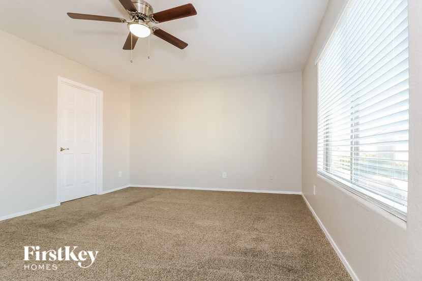 an empty living room with a ceiling fan and a window