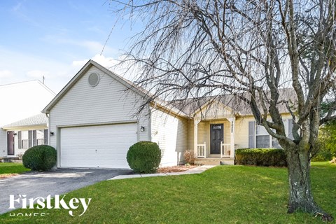 A house with a white garage door and a tree in front.