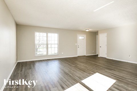A spacious room with wooden flooring and a large window.