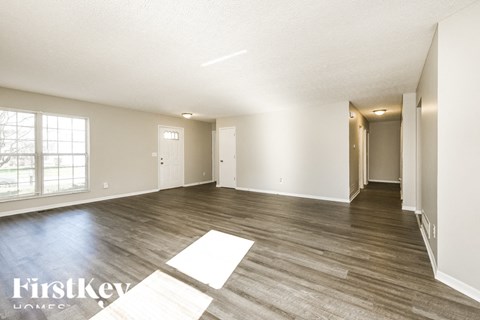 A spacious room with wooden flooring and white walls.