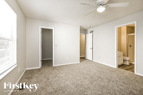 A spacious room with a carpeted floor and a ceiling fan.