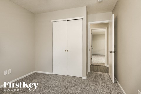 A bedroom with a white closet and a carpeted floor.