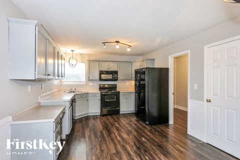 a kitchen with white cabinets and a black refrigerator