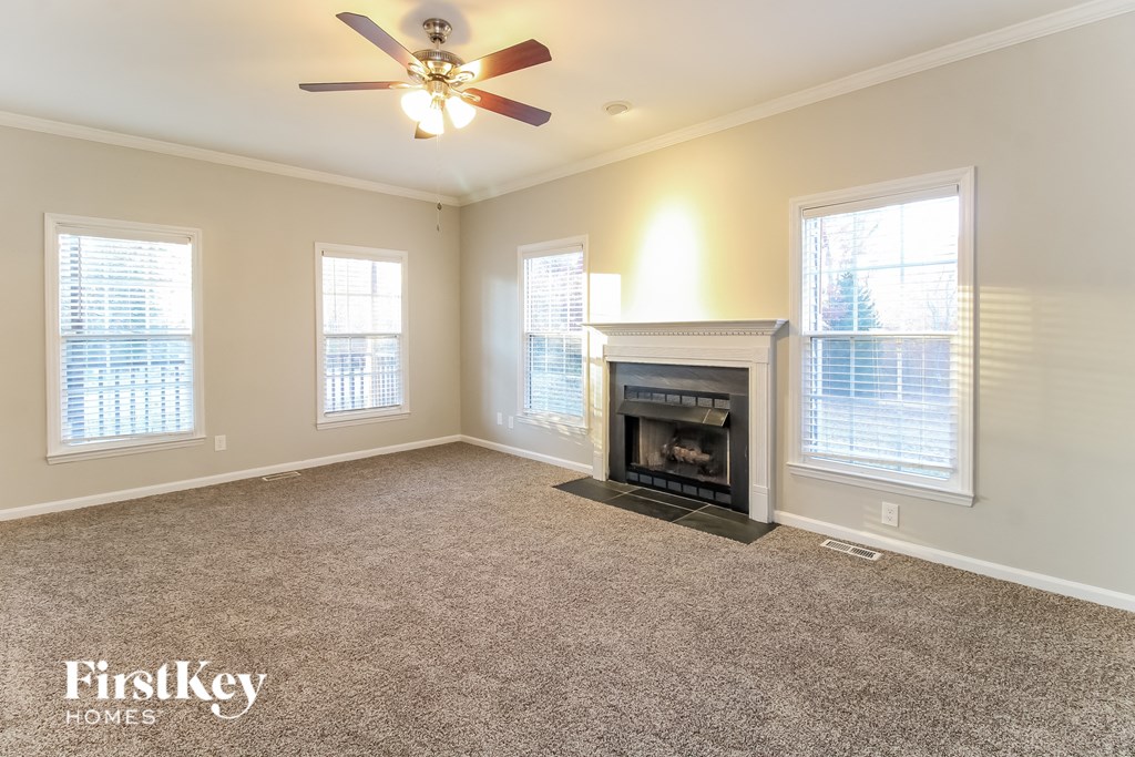 an empty living room with a fireplace and a ceiling fan