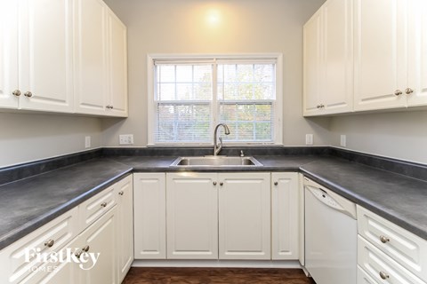 a kitchen with white cabinets and a sink and a window