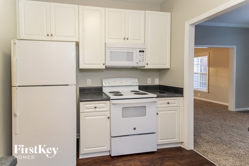 a kitchen with white cabinets and a white stove and refrigerator