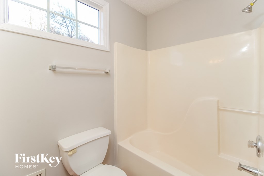 a bathroom with a toilet and a tub and a window