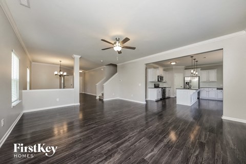 A spacious living room with wood flooring and a ceiling fan.