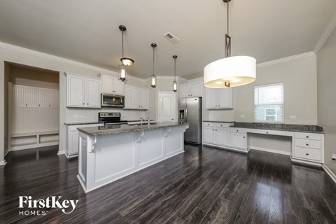 A modern kitchen with white cabinets and dark wood floors.