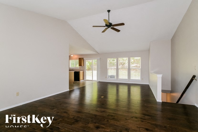 an empty living room with white walls and a ceiling fan