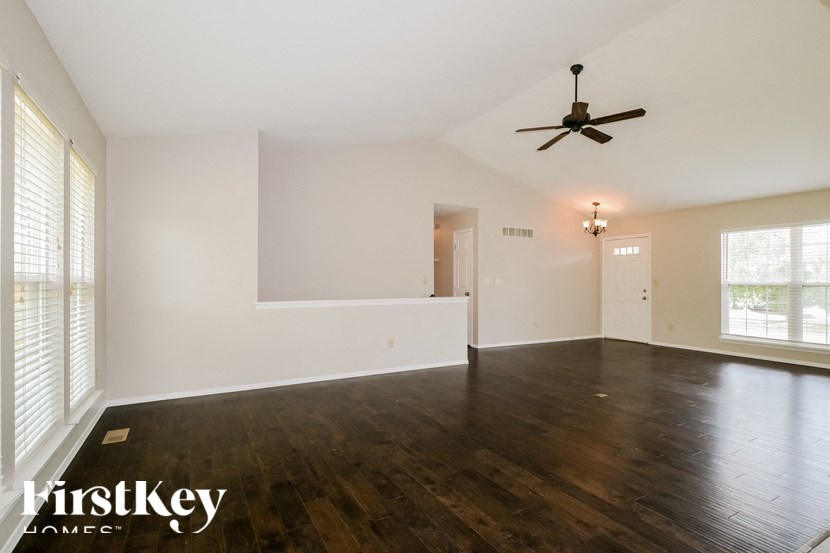 an empty living room with white walls and a ceiling fan