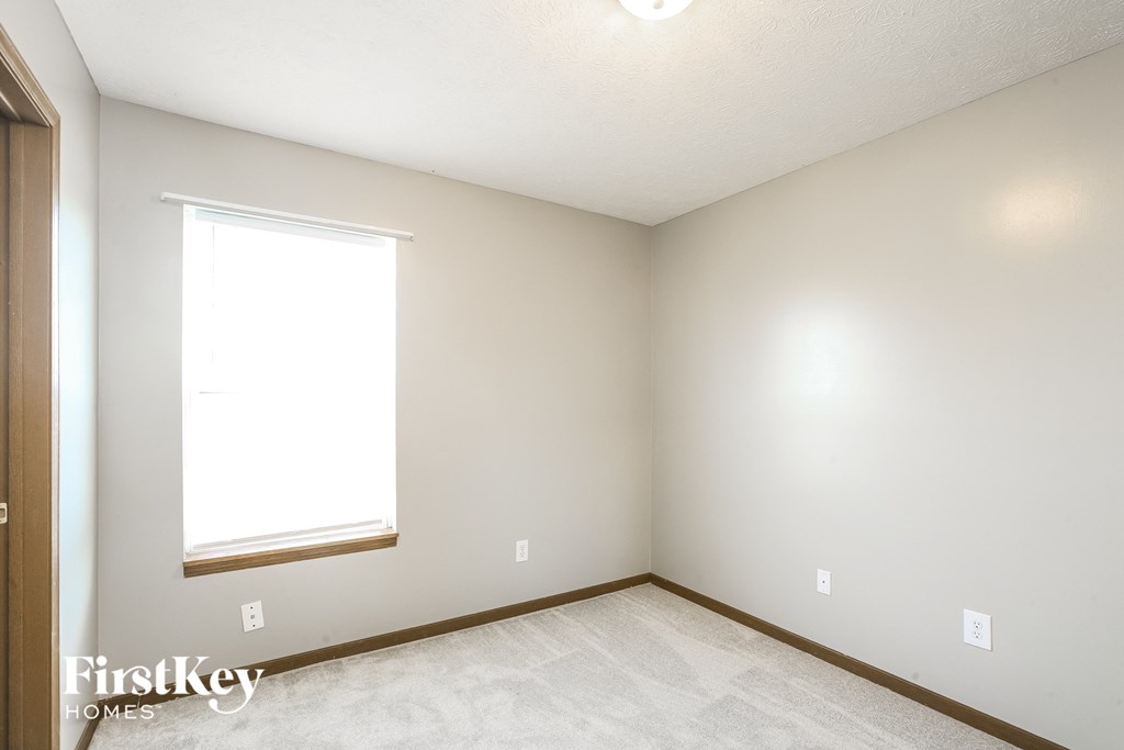 a bedroom with white walls and a window