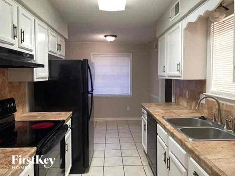 A kitchen with black appliances and white cabinets.