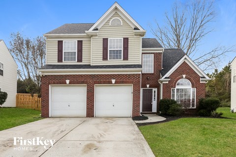a brick house with two garage doors and a lawn
