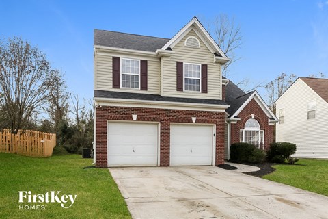 a brick house with two garage doors and a lawn
