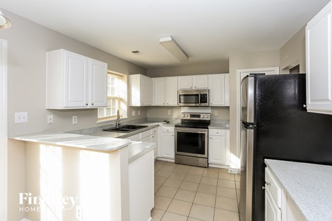 a kitchen with white cabinets and a black refrigerator