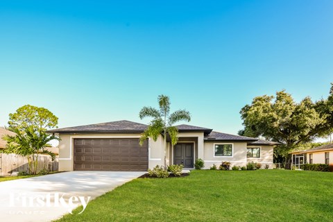 A house with a garage and a tree in front of it.