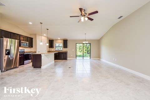 A spacious kitchen with a stainless steel refrigerator and a ceiling fan.