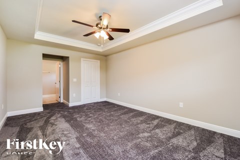 A spacious room with a ceiling fan and a carpeted floor.