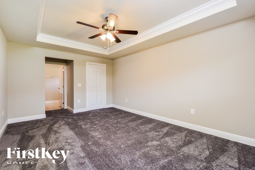 A spacious room with a ceiling fan and a carpeted floor.