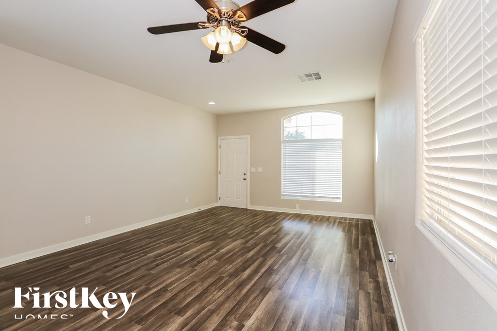 A room with a ceiling fan and wooden flooring.