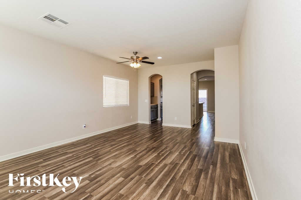 A spacious room with wooden flooring and a ceiling fan.