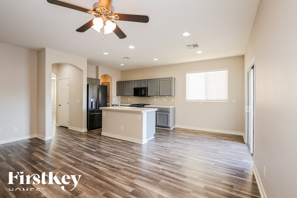 A spacious kitchen with a wooden floor and a ceiling fan.