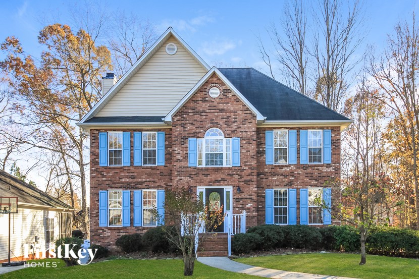 A brick house with a white roof and blue shutters.