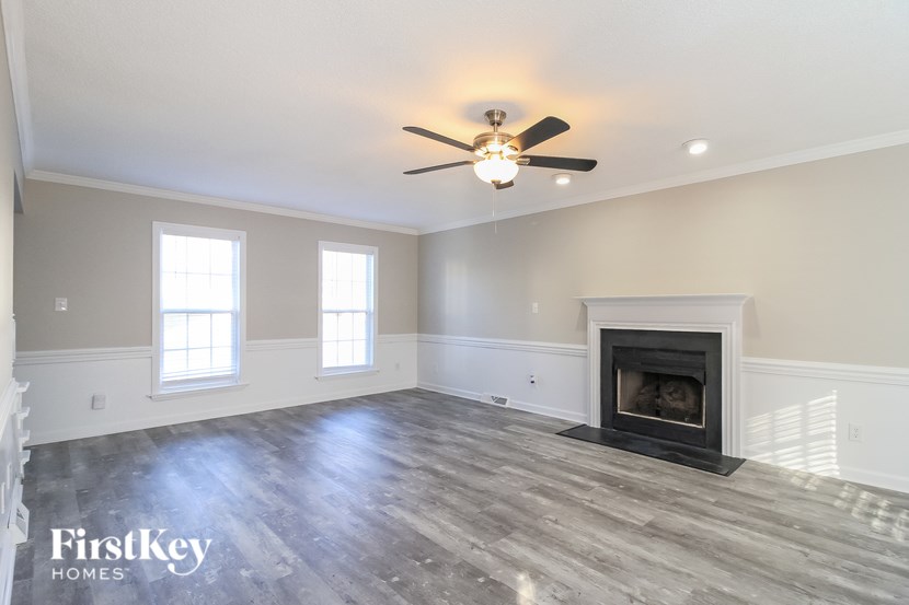 A spacious living room with a fireplace and a ceiling fan.