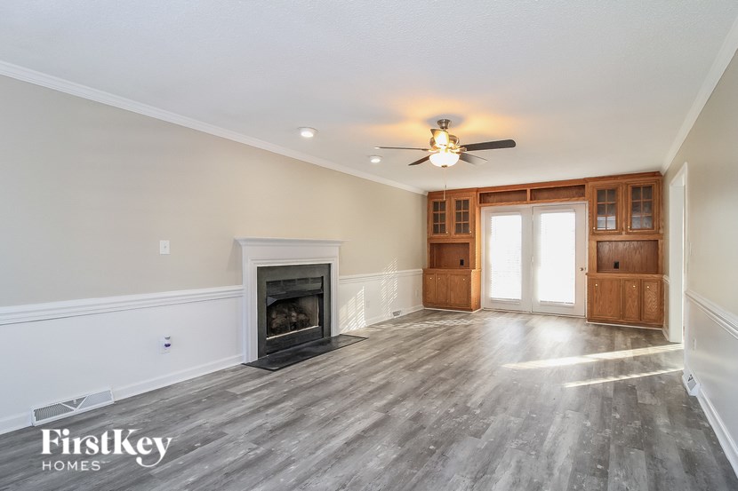 A spacious living room with a fireplace and wooden floors.