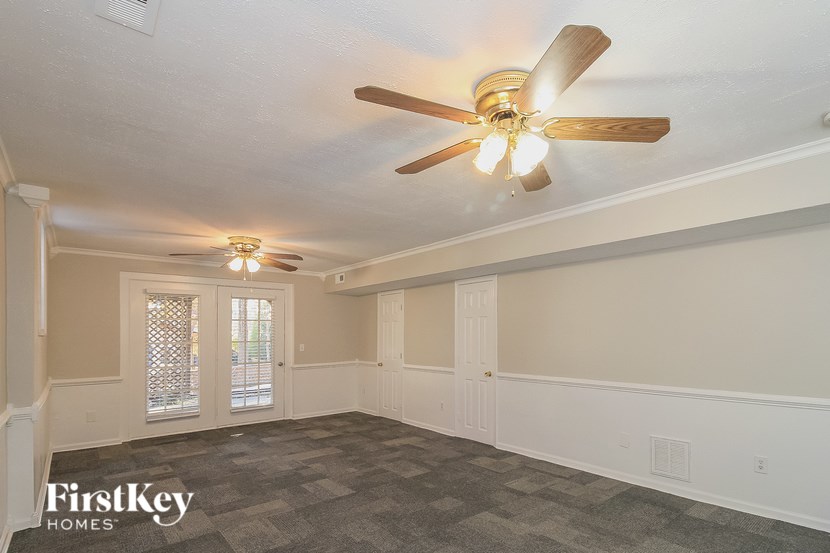 A spacious room with a ceiling fan and two light fixtures.