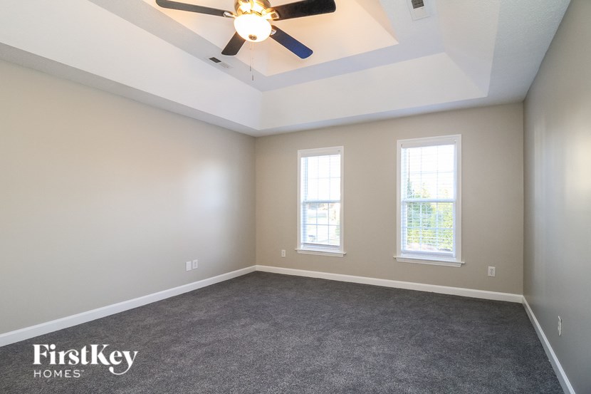 A room with a ceiling fan and two windows.