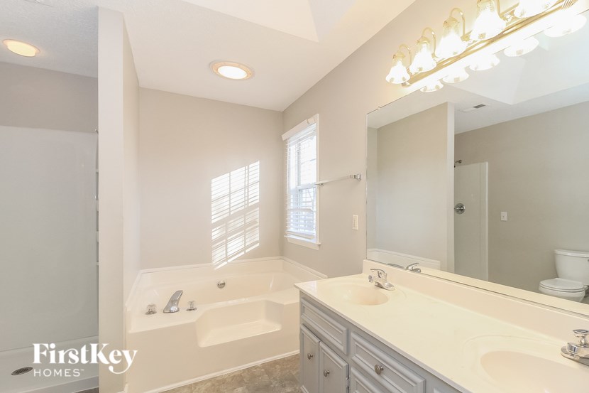 A bathroom with a tub, sink, and mirror.