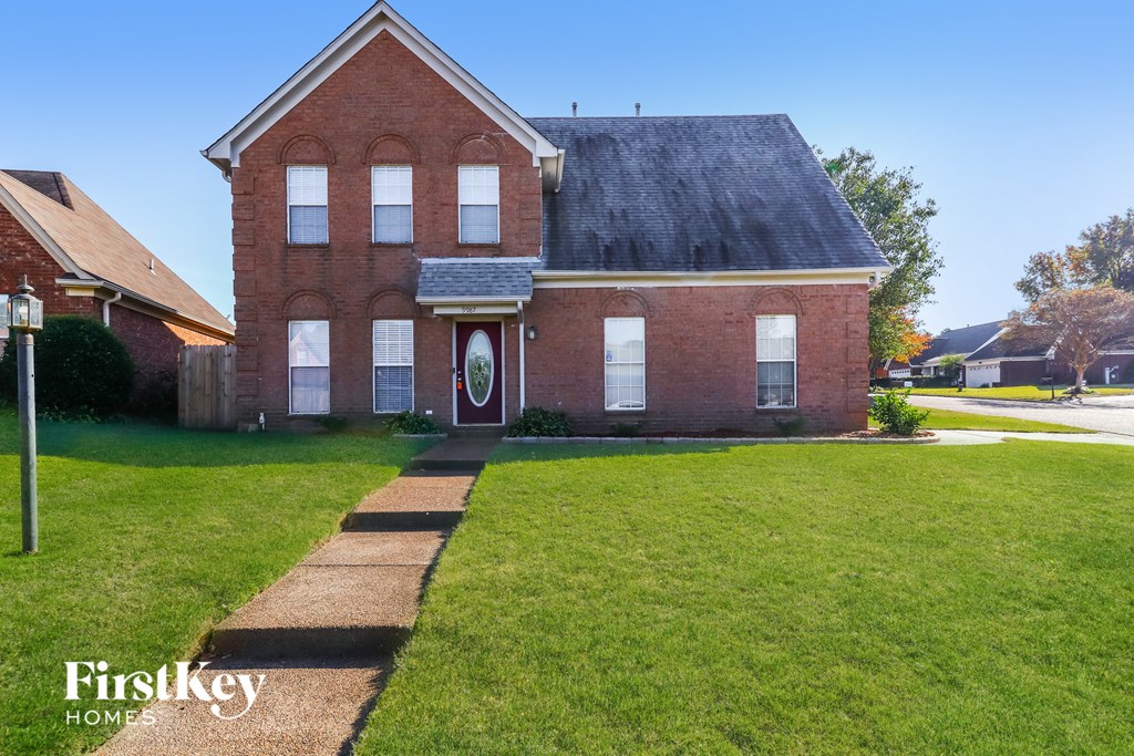 A brick house with a red door and a sign that says Firstkey Homes.
