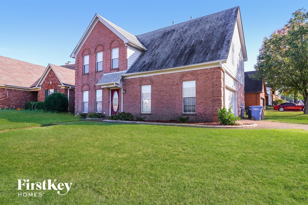 A red brick house with a black roof and a white garage door.