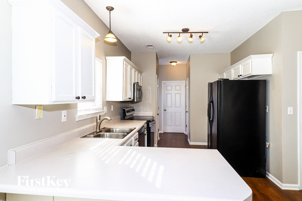 A kitchen with white cabinets and a black refrigerator.